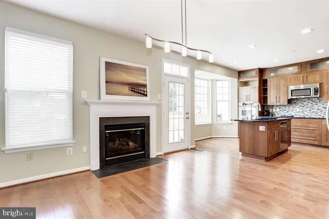 a view of an empty room with wooden floor fireplace and a window