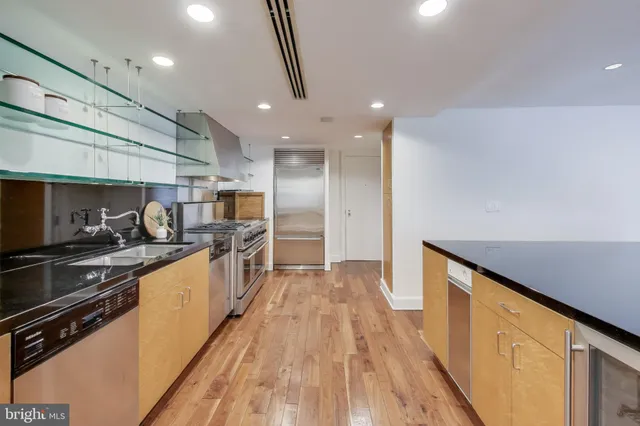 a hallway with stainless steel appliances granite countertop a refrigerator and a stove top oven