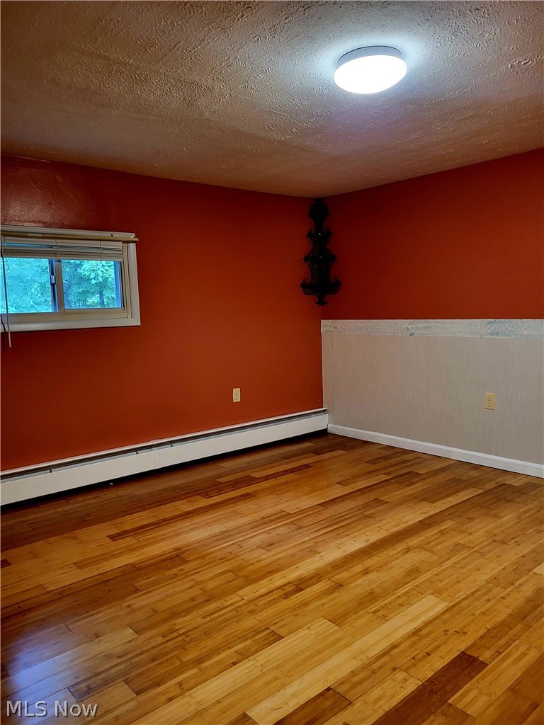 4445 Hamilton Road Medina, OH 44256 - Photo 16 of 41 Spare room with a textured ceiling, a baseboard heating unit, and light hardwood / wood-style floors