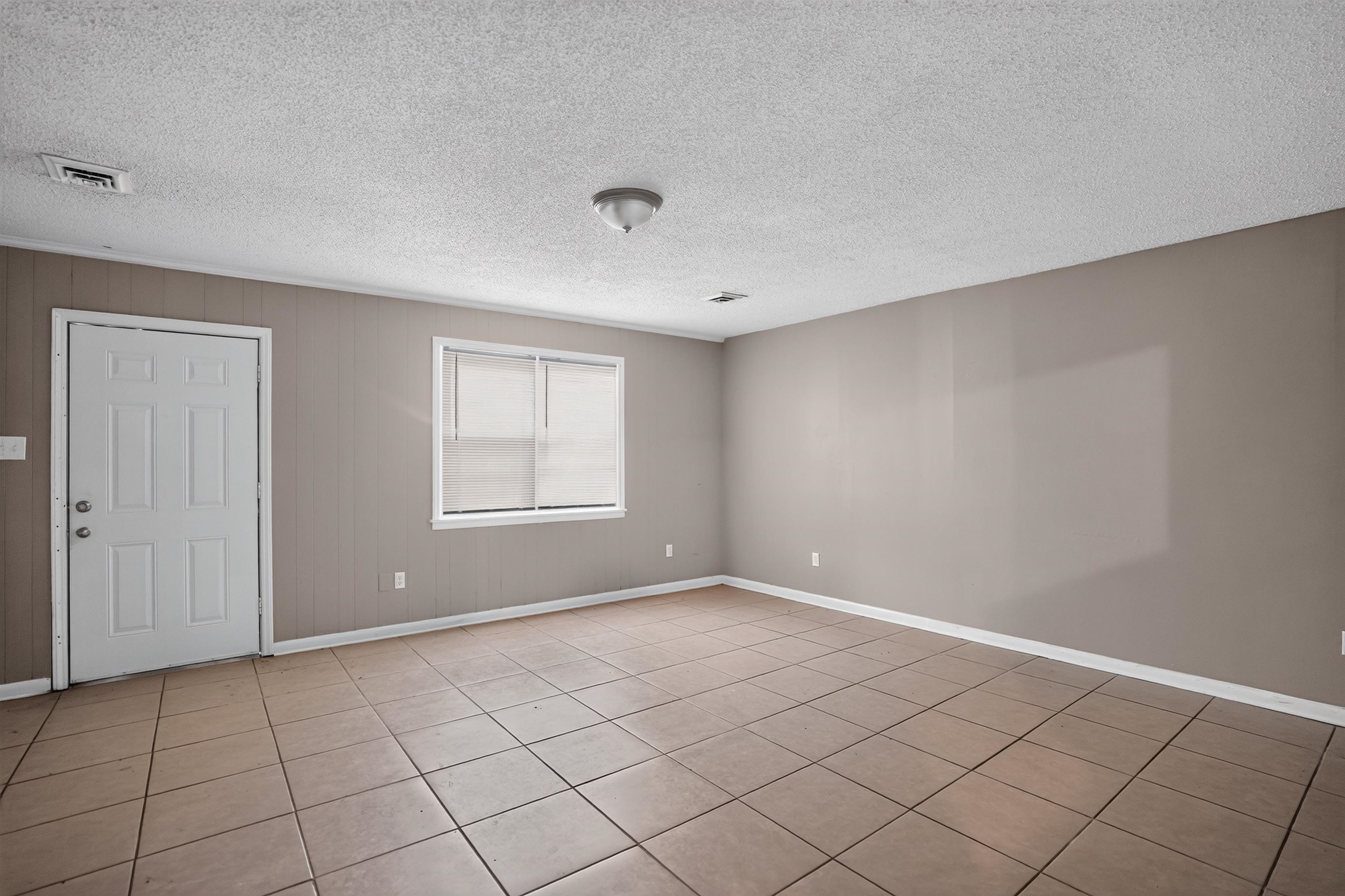 3736 Range Line Road Memphis, TN 38127 - Photo 6 of 18 Spacious room featuring neutral tone walls, tile flooring, a multi-panel door, and a single window with blinds