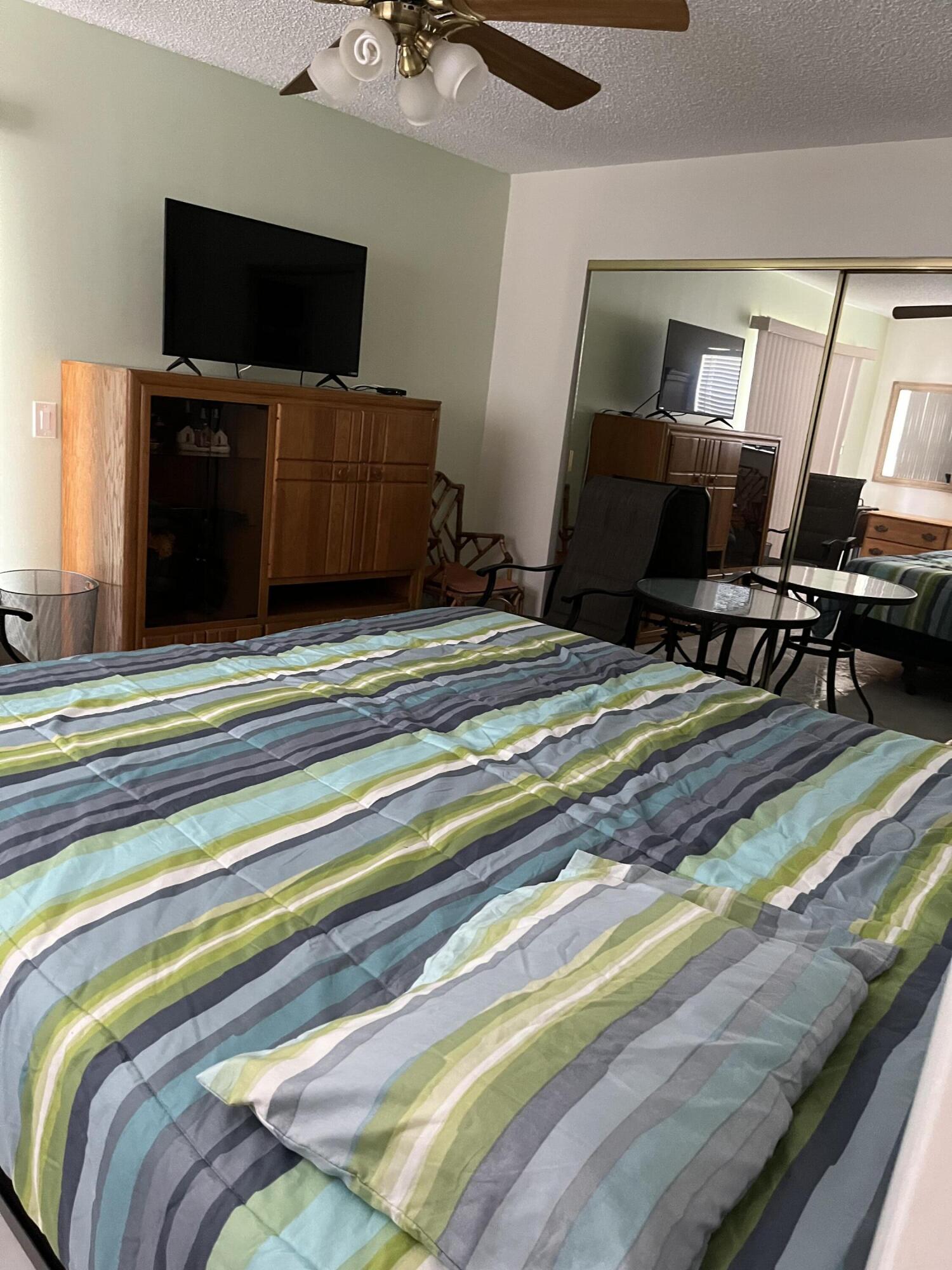 457 Flanders I, Unit 457 Delray Beach, FL 33484 - Photo 6 of 13 a bedroom with a bed and flat screen tv