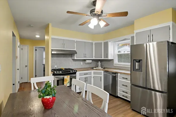 a kitchen with stainless steel appliances granite countertop a refrigerator a stove a sink dishwasher and white cabinets with wooden floor