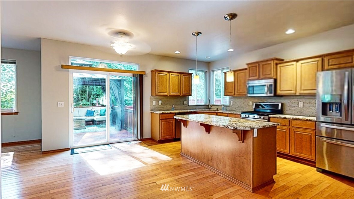 4524 147th Place Southeast Bothell, WA 98012 - Photo 3 of 33 a kitchen with stainless steel appliances granite countertop a refrigerator a sink dishwasher a stove and a dining table with wooden floor