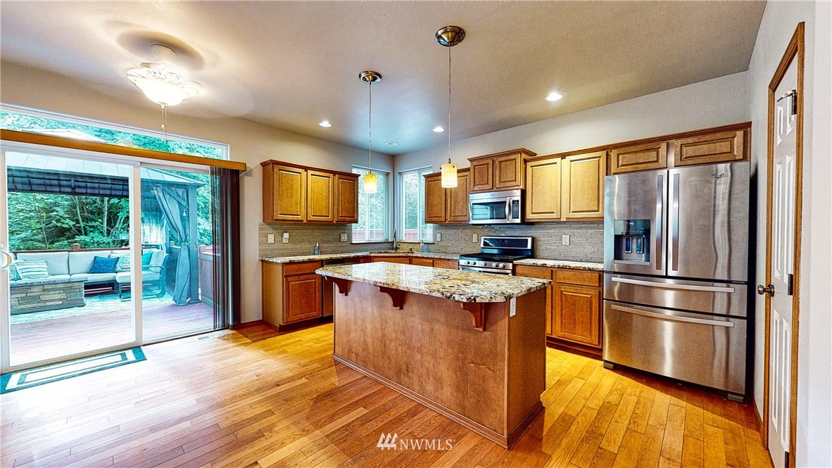 4524 147th Place Southeast Bothell, WA 98012 - Photo 5 of 33 a kitchen with stainless steel appliances granite countertop a refrigerator a sink dishwasher a stove and a dining table with wooden floor