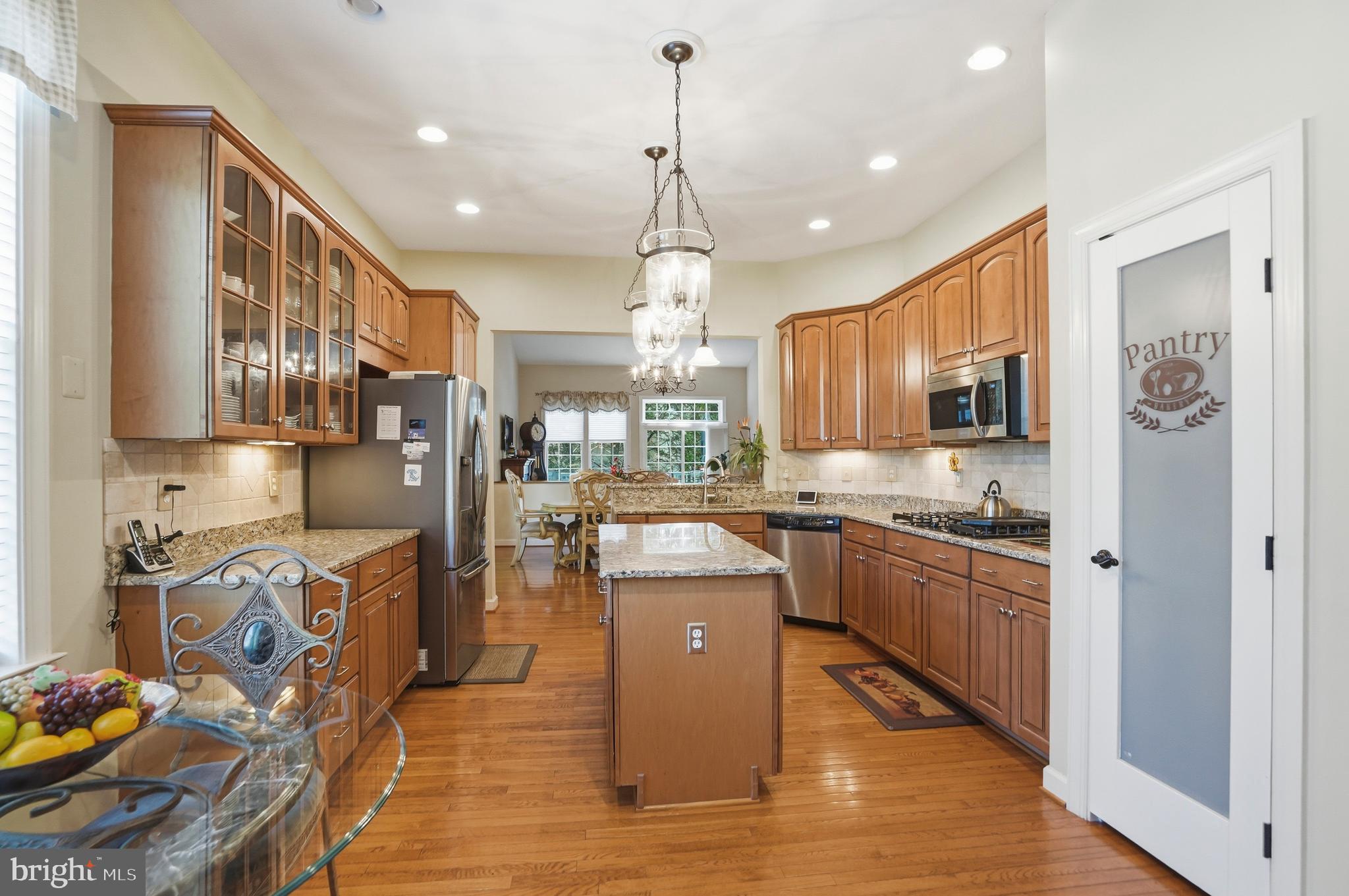 4109 Winterhazel Road, Unit 4109 Baltimore, MD 21208 - Photo 12 of 46 a kitchen with stainless steel appliances granite countertop a refrigerator a stove top oven a sink dishwasher and wooden cabinets with wooden floor