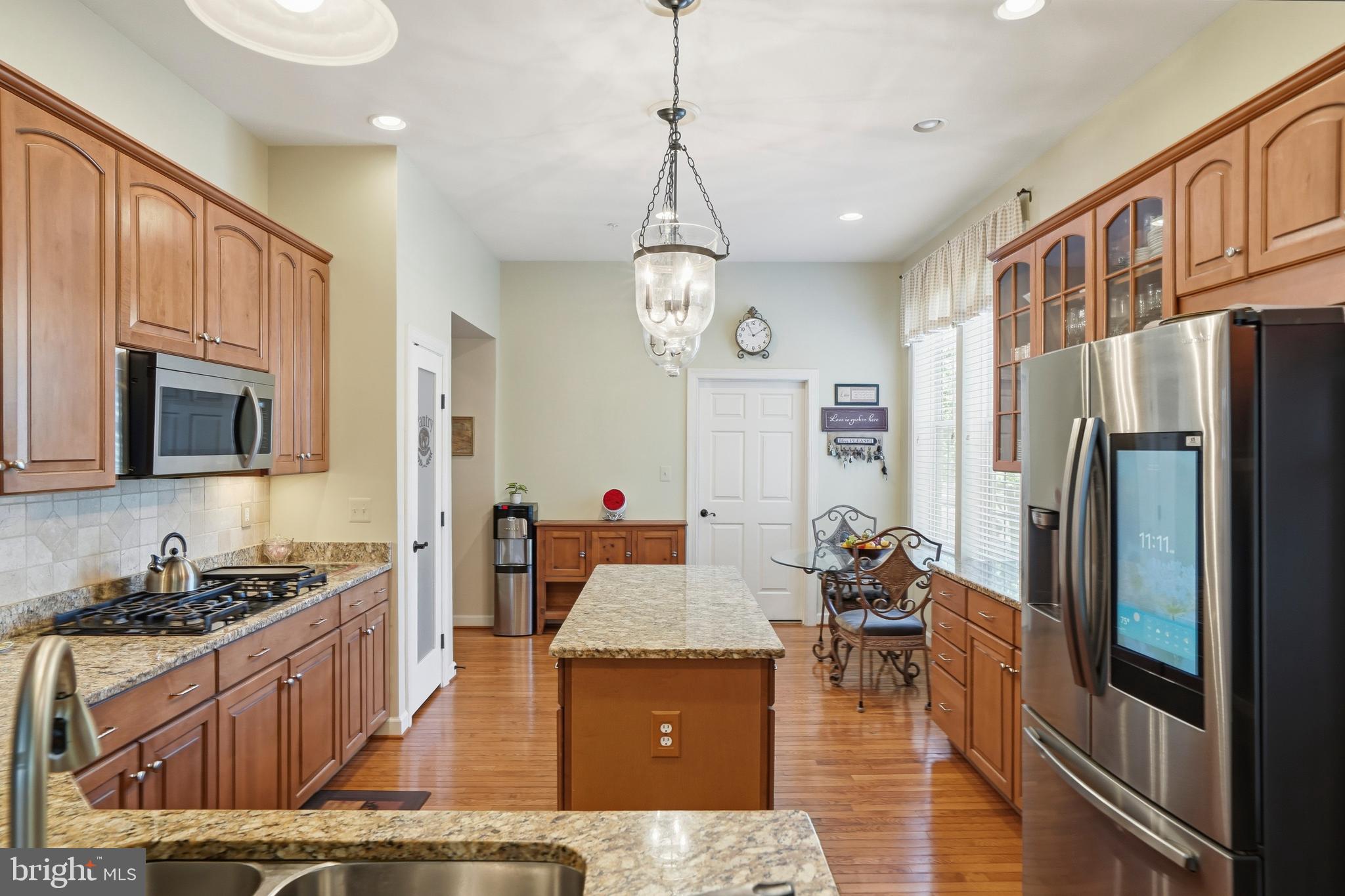 4109 Winterhazel Road, Unit 4109 Baltimore, MD 21208 - Photo 17 of 46 a kitchen with stainless steel appliances granite countertop a refrigerator a stove top oven a sink dishwasher and couches with wooden floor