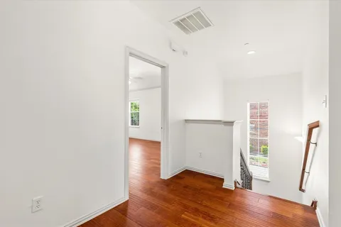 an empty room with wooden floor and a ceiling fan
