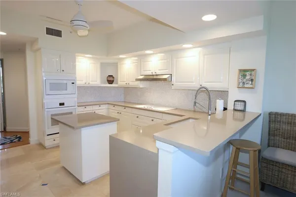 a kitchen with a sink a stove a refrigerator and white cabinets with wooden floor