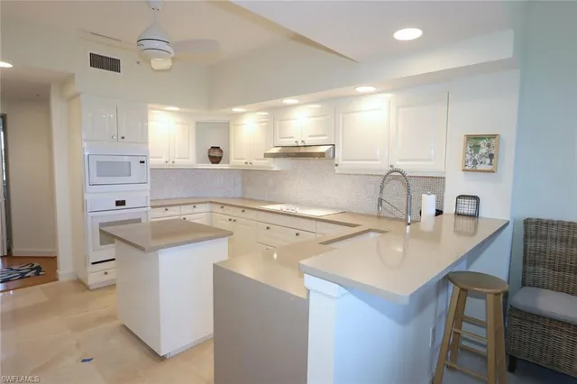 a kitchen with a sink a stove a refrigerator and white cabinets with wooden floor