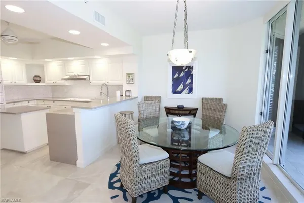 a dining room with stainless steel appliances kitchen island granite countertop a dining table chairs and a refrigerator