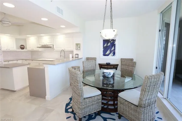 a dining room with stainless steel appliances kitchen island granite countertop a dining table chairs and a refrigerator