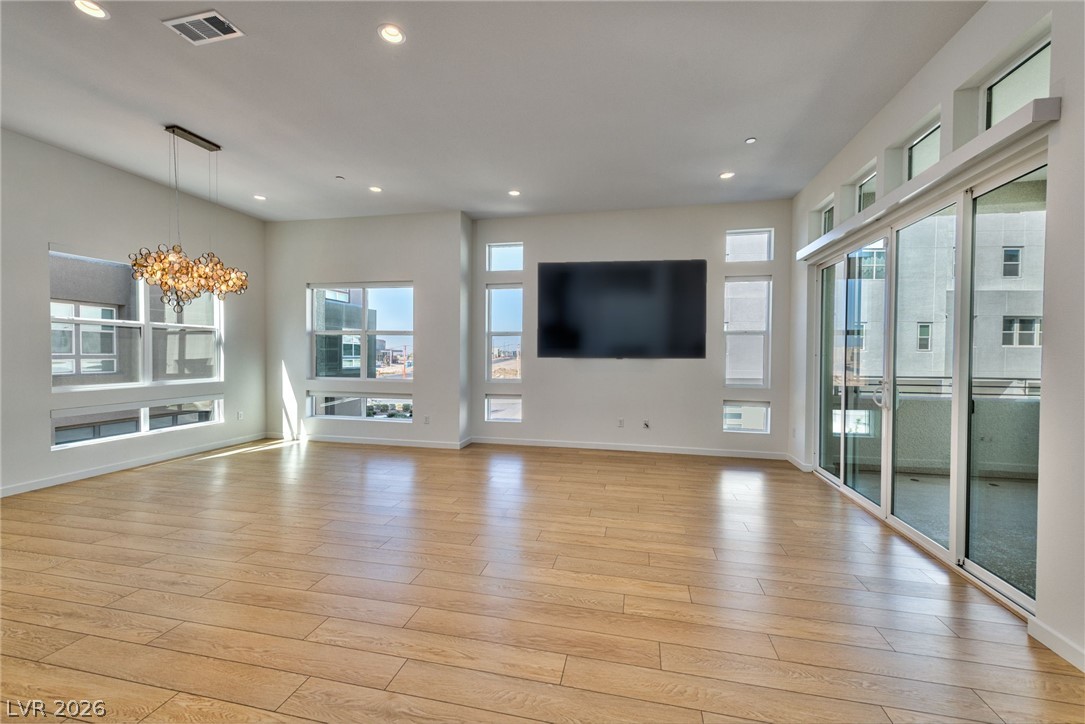 3327 Esker Rdg Avenue Henderson, NV 89044 - Photo 2 of 24 Natural light floods this spacious room, featuring elegant hardwood flooring and abundant window arrangements.