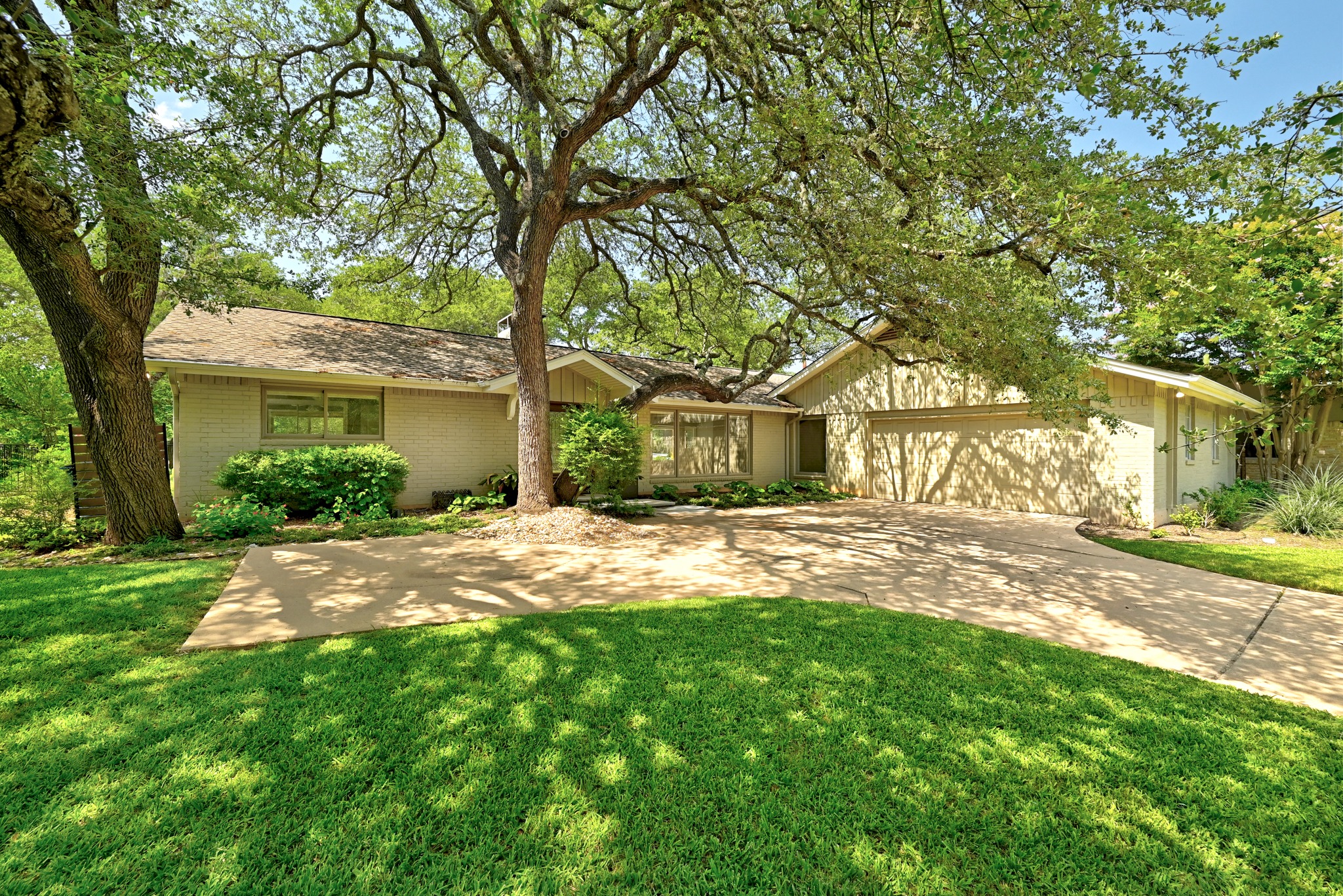 8608 Crest Ridge Circle Austin, TX 78750 - Photo 5 of 38 Mature trees and lush greenery frame a inviting ranch-style residence with a side-entry attached garage.