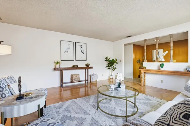a living room with furniture a dining table and paintings on the wall with wooden floor