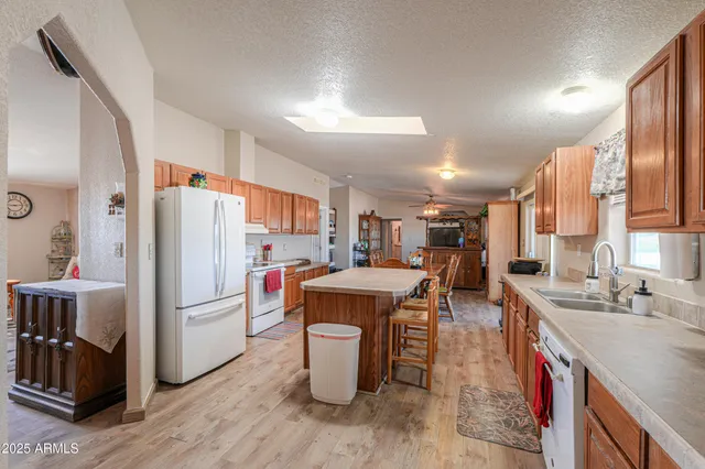 a room with stainless steel appliances kitchen island granite countertop a table chairs sink and cabinets