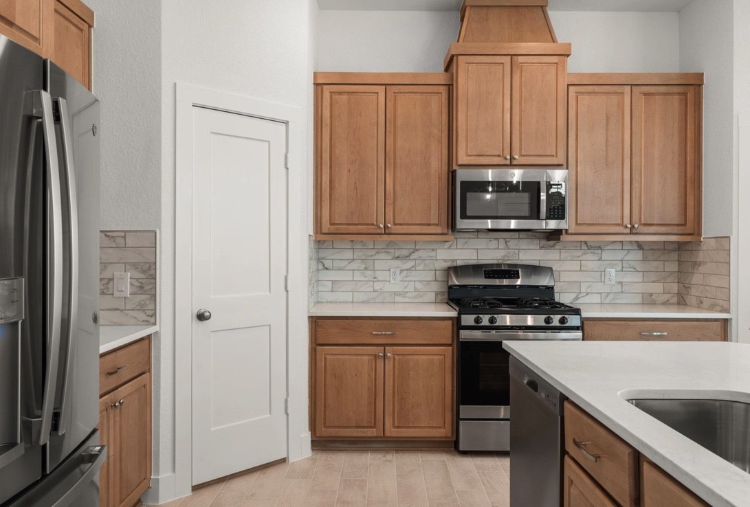 5234 Capricorn Way Manvel, TX 77578 - Photo 9 of 25 a kitchen with stainless steel appliances a stove a sink and a refrigerator with cabinets