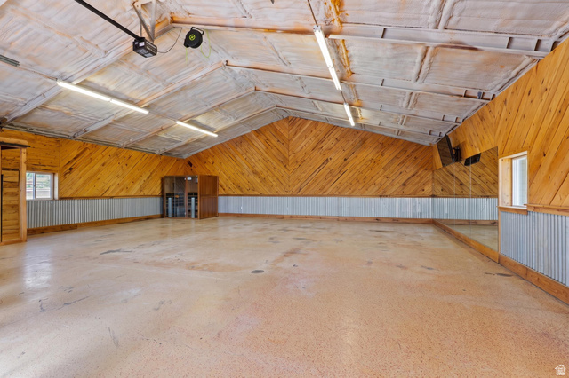 115 East 1600th Street North Santaquin, UT 84655 - Photo 43 of 52 Spacious interior featuring a high vaulted ceiling with exposed insulation, wood-paneled walls, corrugated metal wainscoting, and a polished concrete floor