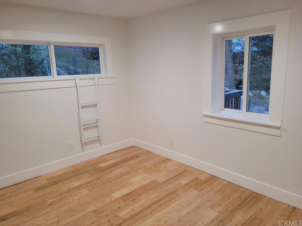 582 Sunset View Road Twin Peaks, CA 92391 - Photo 10 of 18 a view of an empty room with wooden floor and a window