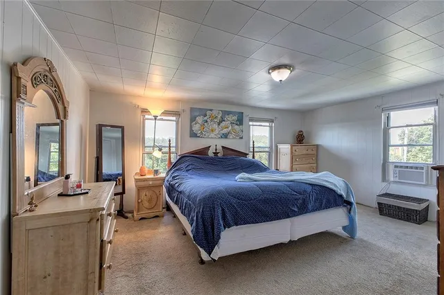 a spacious bedroom with a bed couch chandelier and a window