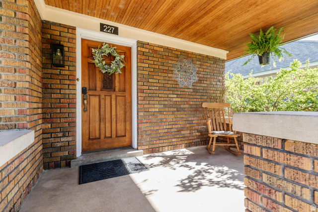 227 West 200 North Logan, UT 84321 - Photo 7 of 44 Brick exterior featuring a wood-panel ceiling, solid wood entry door, and concrete porch