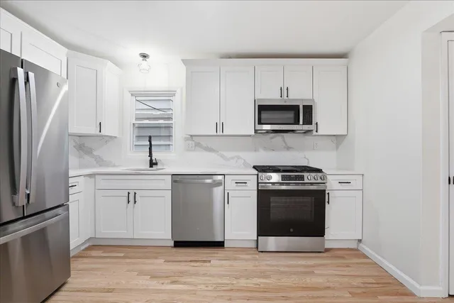 a kitchen with white cabinets stainless steel appliances and sink