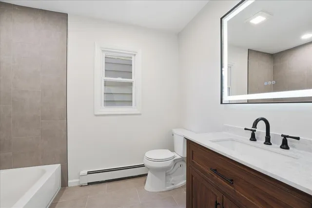 a bathroom with a toilet a sink a mirror and bathtub