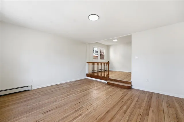 a view of an empty room with wooden floor and windows