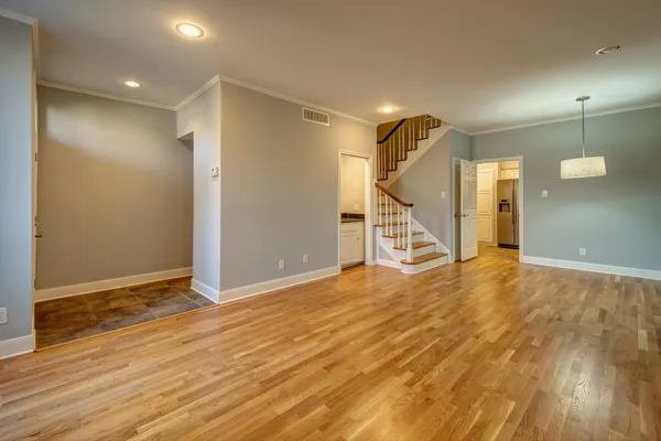a view of an empty room with wooden floor and stairs