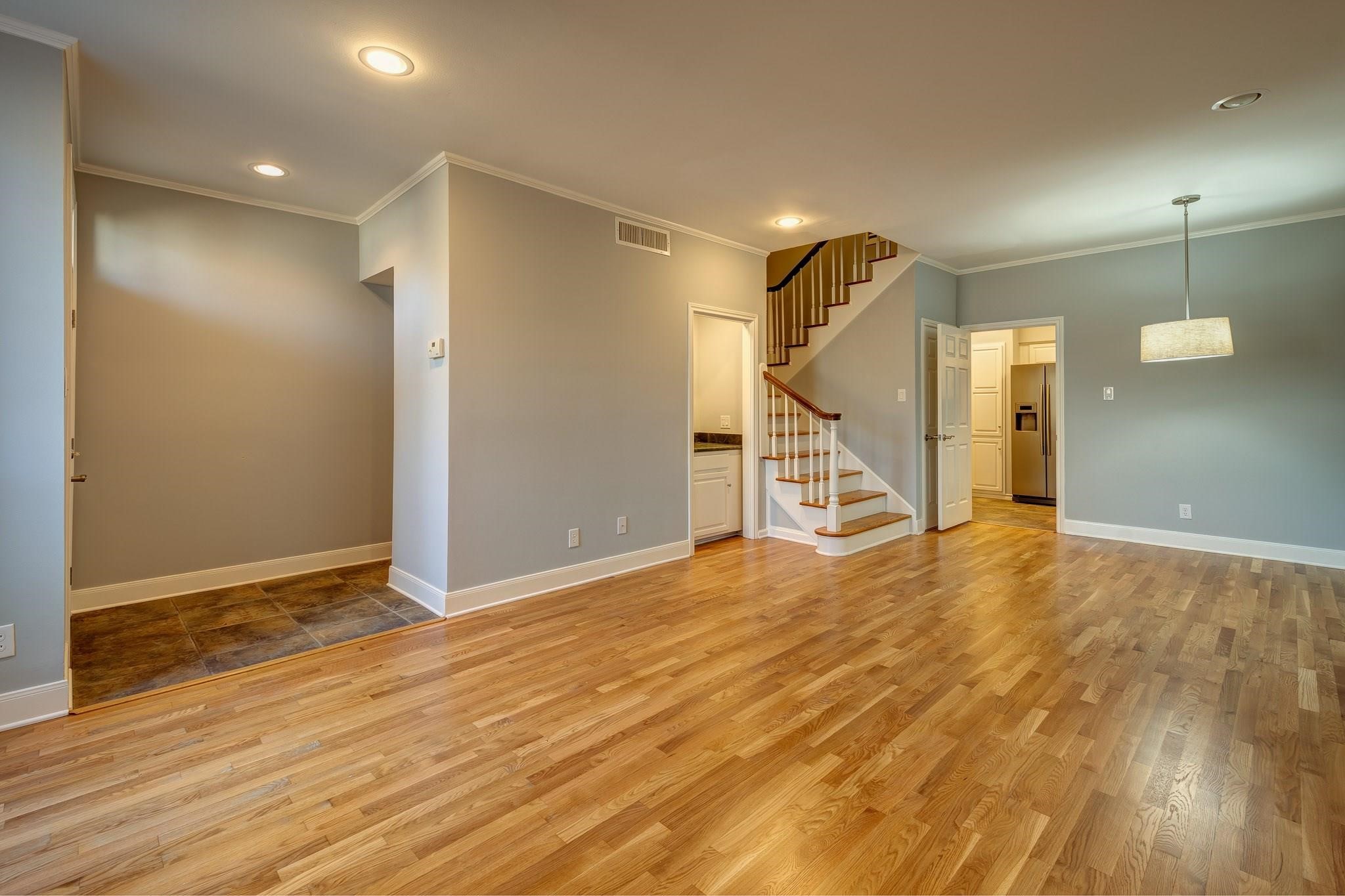 a view of an empty room with wooden floor and stairs