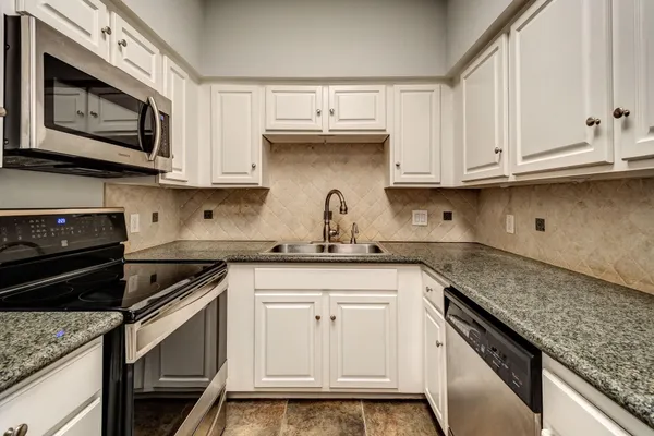 a kitchen with granite countertop white cabinets and a stove top oven