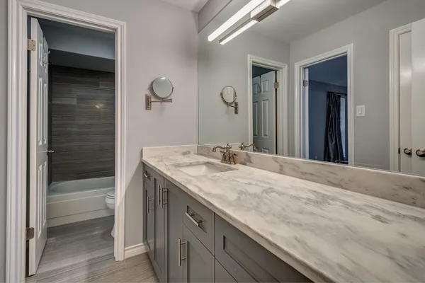 a bathroom with a granite countertop sink a toilet and shower