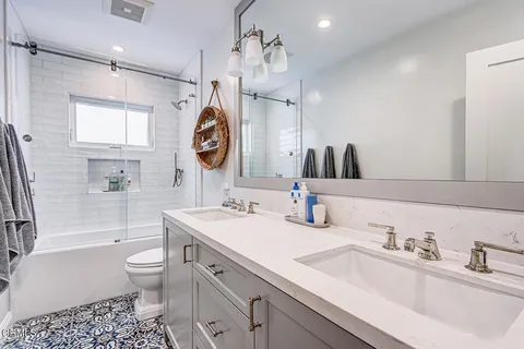 a bathroom with a sink a toilet a mirror and shower