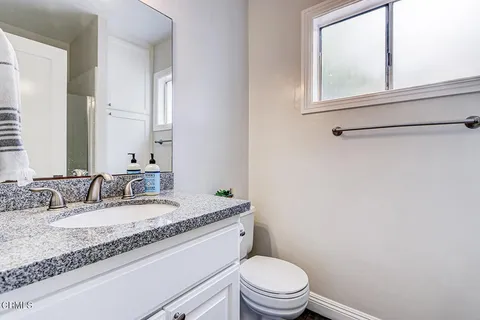 a bathroom with a granite countertop sink mirror vanity and toilet