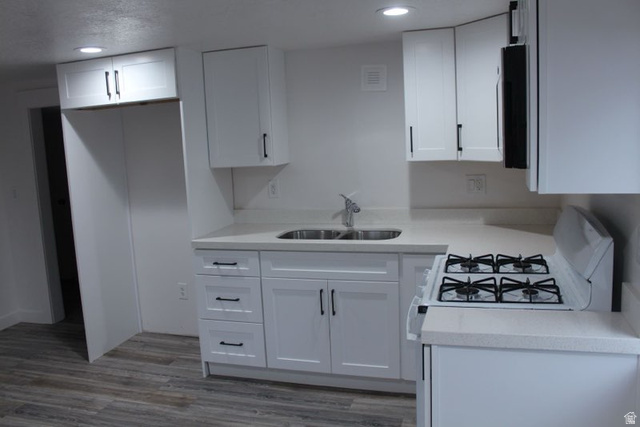 545 100 East Bountiful, UT 84010 - Photo 8 of 17 Kitchen with white gas range oven, white cabinetry, light wood-style flooring, and recessed lighting