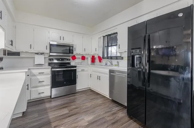 a kitchen with a sink stainless steel appliances and white cabinets