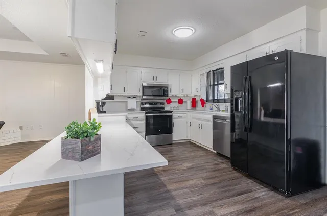 a kitchen with kitchen island white cabinets and stainless steel appliances
