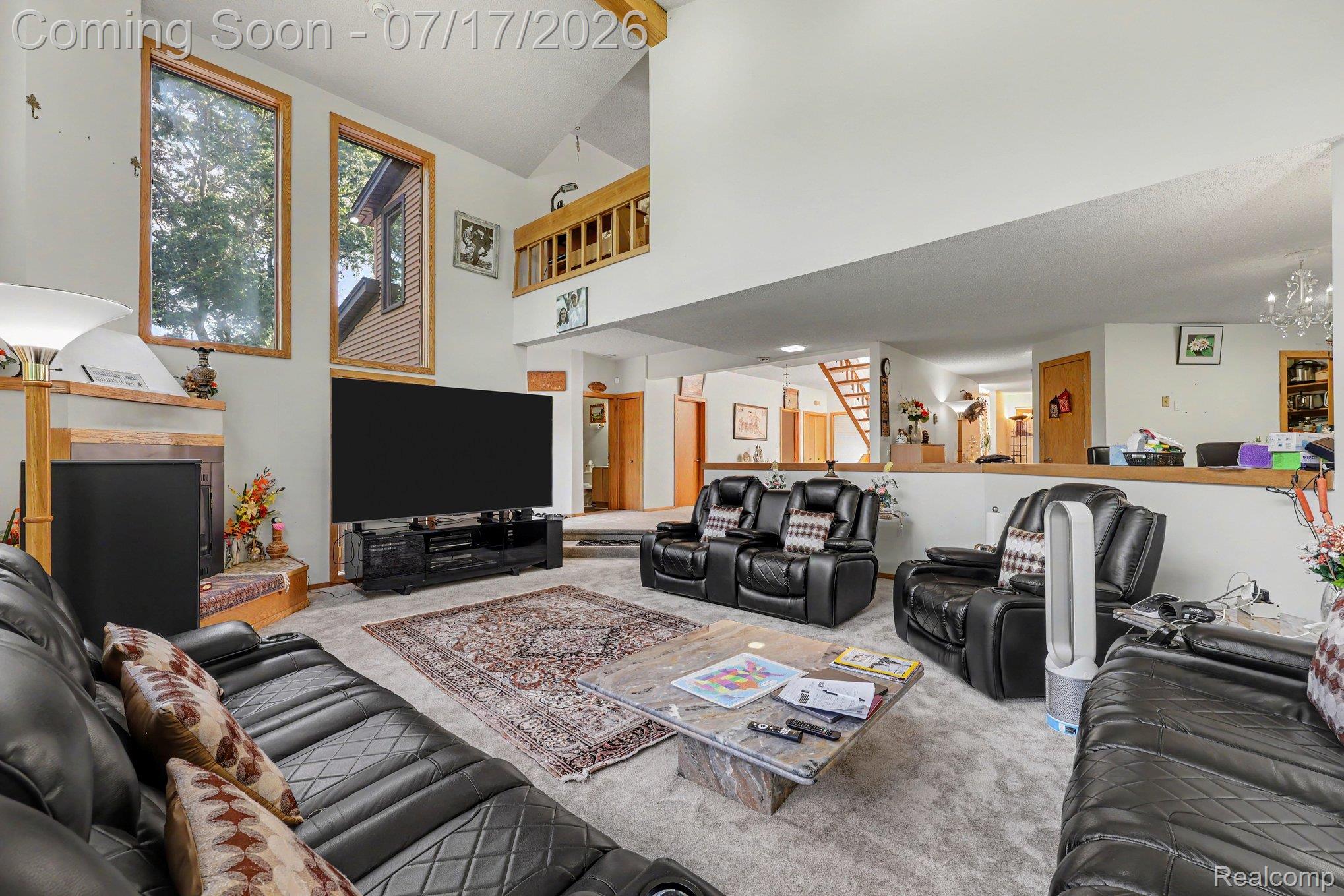 5685 Paint Valley Drive Rochester, MI 48306 - Photo 10 of 66 Vaulted ceiling living area featuring a fireplace with a wood mantel, oversized windows with wood trim, and a carpeted floor