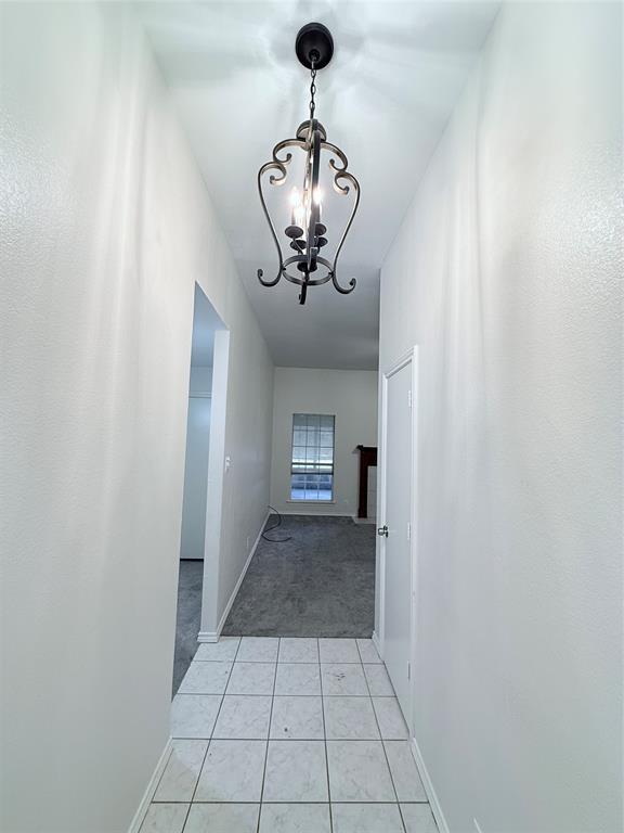 313 Pear Tree Place Denton, TX 76207 - Photo 3 of 23 Hallway with a chandelier, light tile patterned floors, and light colored carpet