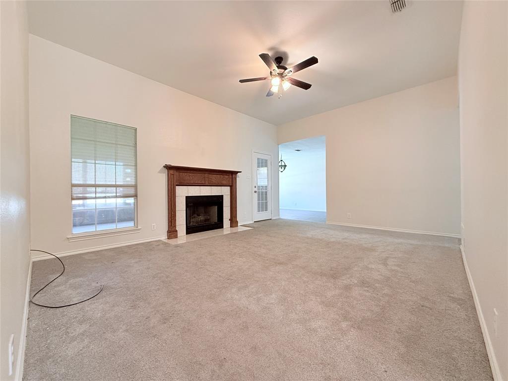 313 Pear Tree Place Denton, TX 76207 - Photo 5 of 23 Unfurnished living room featuring light carpet, a tiled fireplace, and ceiling fan