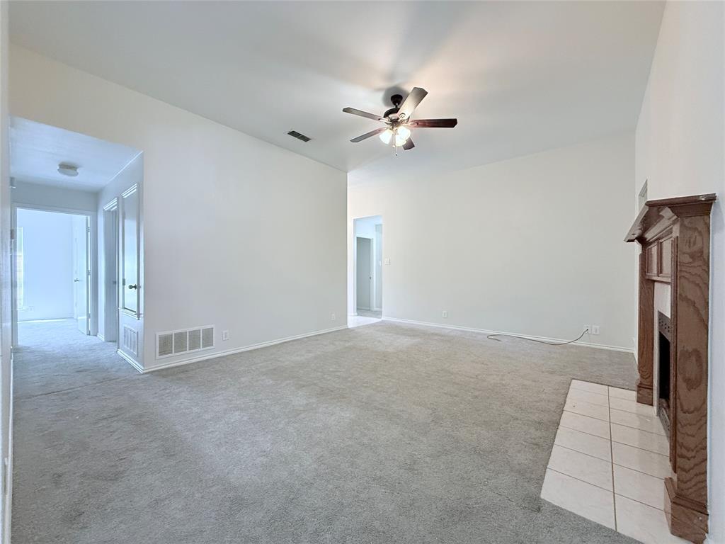 313 Pear Tree Place Denton, TX 76207 - Photo 7 of 23 Unfurnished living room with light carpet, a brick fireplace, and ceiling fan