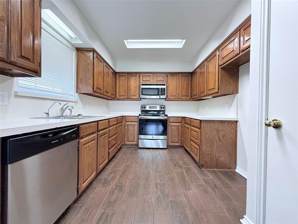 313 Pear Tree Place Denton, TX 76207 - Photo 8 of 23 Kitchen with appliances with stainless steel finishes, brown cabinets, and light countertops