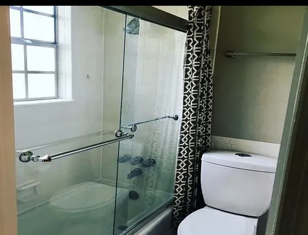 a white toilet sitting next to a shower