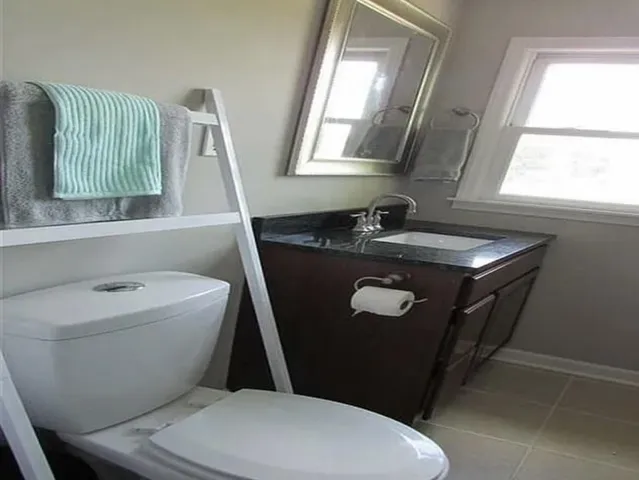 a bathroom with a granite countertop toilet sink and mirror