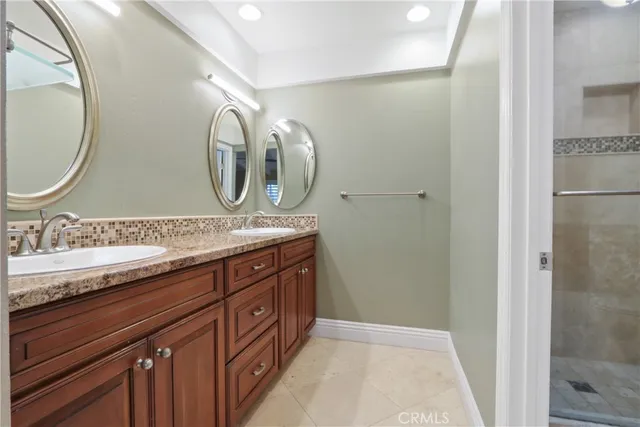a bathroom with a granite countertop double vanity and a mirror