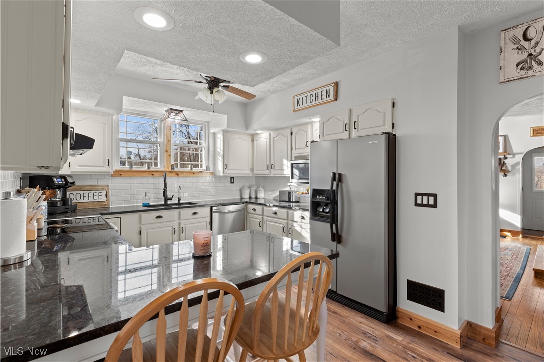 71963 W Road Martins Ferry, OH 43935 - Photo 10 of 39 Kitchen with appliances with stainless steel finishes, arched walkways, decorative backsplash, and wood finished floors