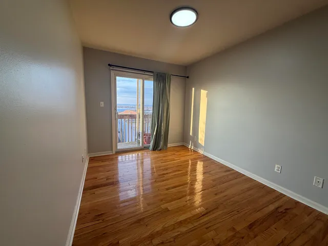 a view of an empty room with window and wooden floor