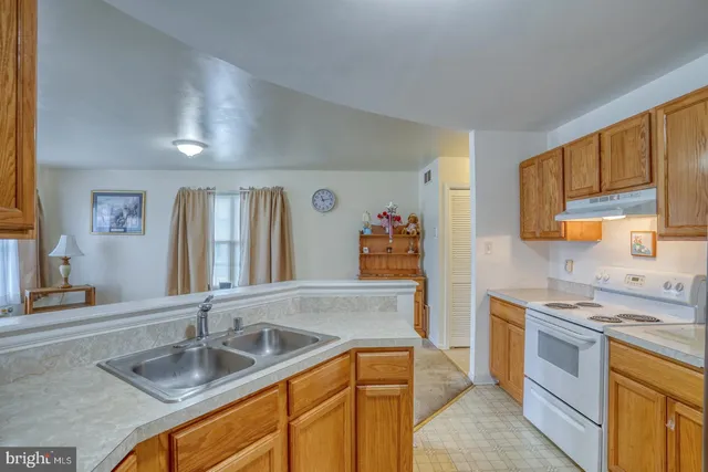 a kitchen that has a sink a stove counter top space and cabinets