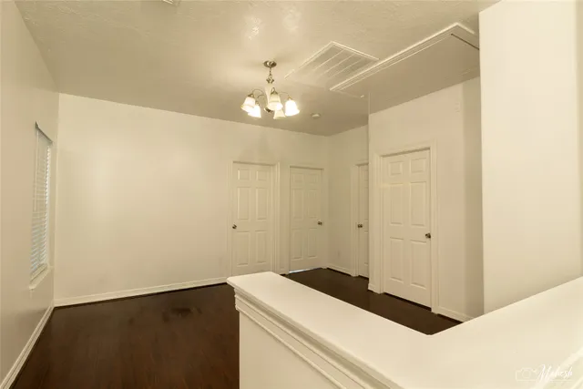 an empty room with wooden floor closet and windows
