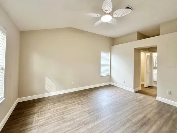 a view of an empty room with window and wooden floor