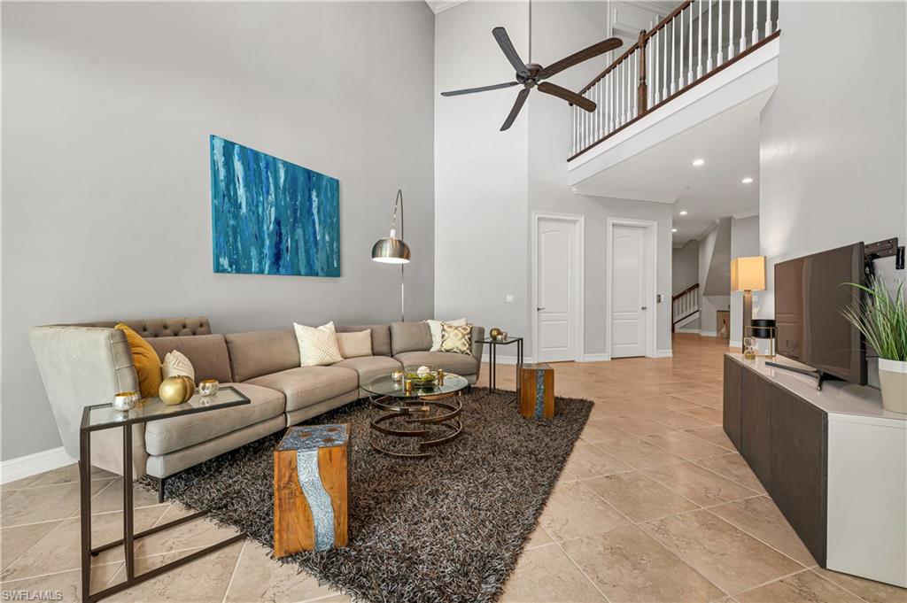 4819 West Blvd Court, Unit 103 Naples, FL 34103 - Photo 2 of 19 a living room with furniture a flat screen tv and a refrigerator